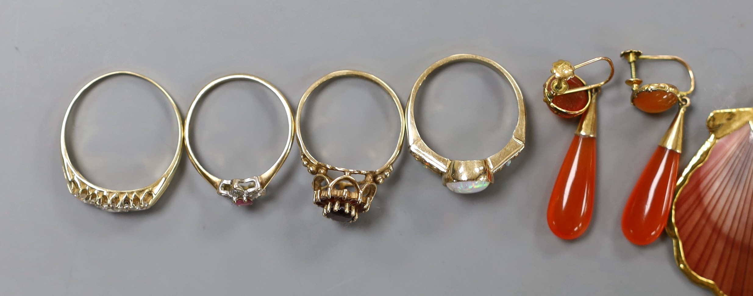Eight assorted modern 9ct gold and gem set dress rings, a pair of 9ct and carnelian set drop earrings, gross weight 30.7 grams. and a yellow metal mounted shell pendant.